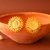 Gold earrings on a terracotta bowl with a warm brown background